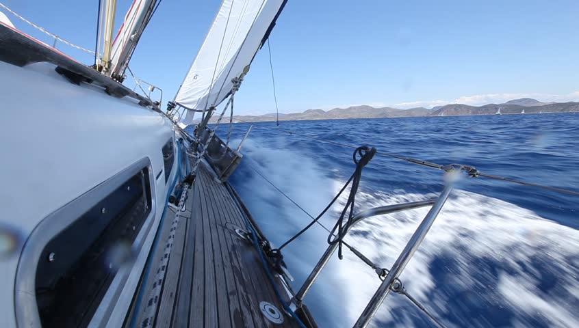Sailboat heeled over and moving fast through open blue water